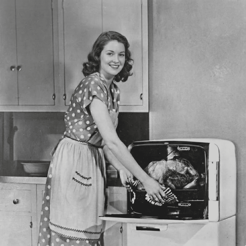 Me in my younger years in a vintage kitchen, smiling while pulling a roast from the oven