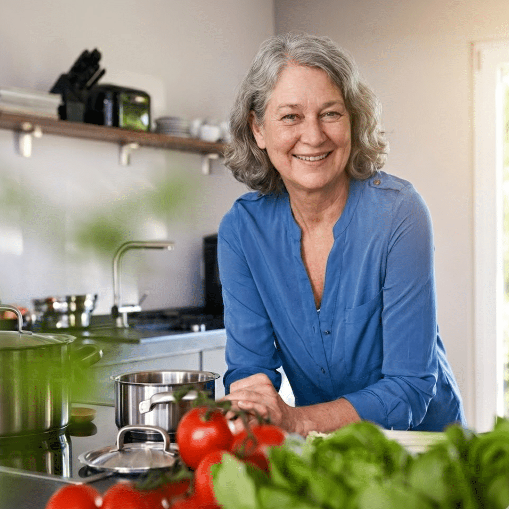 Me smiling in my home kitchen, standing behind a pot and fresh vegetables on the counter