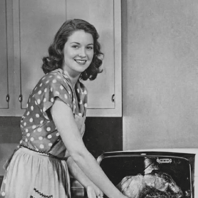 About us 1 Me in my younger years in a vintage kitchen, smiling while pulling a roast from the oven