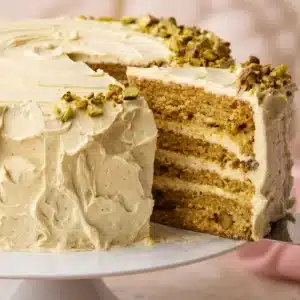 Slice of Pistachio Cream Cake topped with chocolate ganache and pistachio cream.